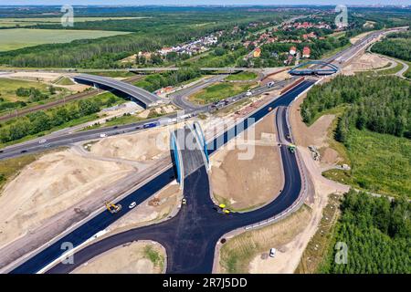 Leipzig, Deutschland. 12. Juni 2023. Die erste Asphaltschicht wurde bereits auf die zukünftige Fahrbahn der A72 am Zwenkau-Kreuz bei Großdeuben aufgetragen. Die Kluft zwischen den A72 und den A38 Jahren sollte bis Mitte Juli geschlossen sein. Bis 2026 sollen die meisten Neubauarbeiten abgeschlossen sein, und der Verkehr von Vogtland nach Leipzig wird auf zwei Fahrspuren fahren können. Der Bau der Lückenschließung ist komplex, da die Strecke über die Ablageflächen eines ehemaligen Tagebaues führt. (Luftfoto mit Drohne) Kredit: Jan Woitas/dpa/Alamy Live News Stockfoto