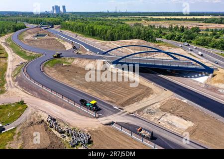 Leipzig, Deutschland. 12. Juni 2023. Die erste Asphaltschicht wurde bereits auf die zukünftige Fahrbahn der A72 am Zwenkau-Kreuz bei Großdeuben aufgetragen. Die Kluft zwischen den A72 und den A38 Jahren sollte bis Mitte Juli geschlossen sein. Bis 2026 sollen die meisten Neubauarbeiten abgeschlossen sein, und der Verkehr von Vogtland nach Leipzig wird auf zwei Fahrspuren fahren können. Der Bau der Lückenschließung ist komplex, da die Strecke über die Ablageflächen eines ehemaligen Tagebaues führt. (Luftfoto mit Drohne) Kredit: Jan Woitas/dpa/Alamy Live News Stockfoto