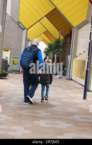 Ein liebevoller Vater, der seinem Sohn hilft, sich auf die Schule vorzubereiten, indem er seinen Rucksack trägt Stockfoto
