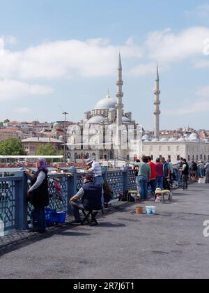 Einheimische fischen auf der Galata Brücke mit der Yeni Cami Moschee im Hintergrund. Istanbul, Türkei Stockfoto