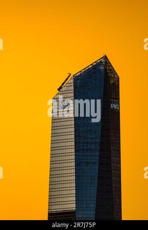 Madrid, Spanien - 17. August 2022: KPMG Tower im Geschäftsviertel Cuatro Torres. Blick bei Sonnenuntergang mit einem dramatischen gelben Himmel. Teleobjektiv Stockfoto