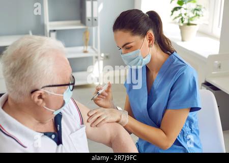 Krankenschwester, die dem älteren männlichen Patienten eine Impfdosis gibt Stockfoto