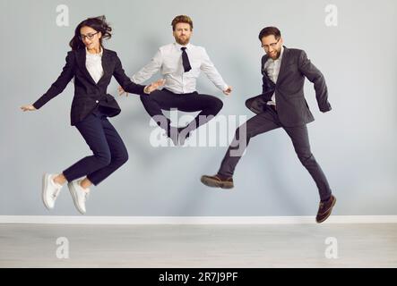 Ein Team von lustigen, glücklichen, verrückten Geschäftsleuten, die im Büro spazieren gehen und Spaß haben Stockfoto