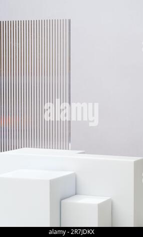 Weißer Sockel zeigt grauen Hintergrund mit modernem Transparentstreifen-Glas mit Sonnenlicht an Stockfoto