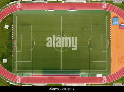 Vogelperspektive von oben auf das Sportcenter für Fußballspiele mit Spielern, die auf grünem Gras laufen Stockfoto