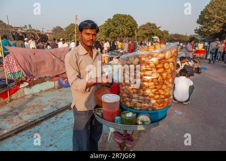 Delhi, Indien - 17. November 2011: Straßenhändler verkauft süße Zuckergetränke und zubereitete Kartoffeln auf seinem Fahrrad an die Menschen. Stockfoto