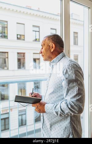 Porträt-Mann mittleren Alters, der Notizen in Notizbuch macht Stockfoto