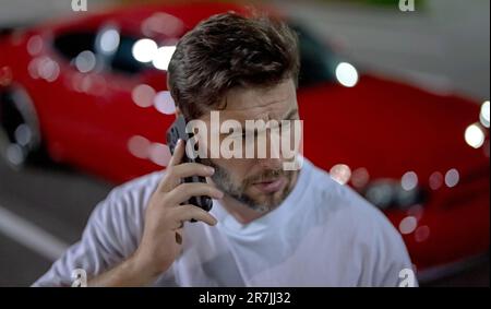 Aggressiver, brutaler Mann. Hipster-Porträt sieht brutal aus. Verärgerter, brutaler Kerl in der Nähe eines Autos auf der Night City Street. Frustration und Gefahr. Ein ernster Mann draußen. Stockfoto