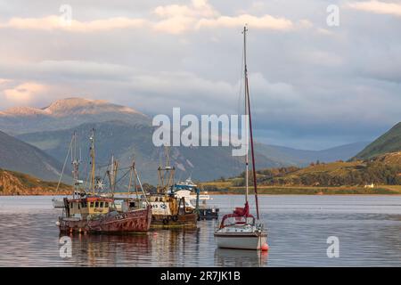 Verankerte Trawler und Segelyacht beleuchtet vom Abendlicht, Loch Groom, Ullapool, Ross und Cromarty, Schottland, Vereinigtes Königreich, Großbritannien Stockfoto