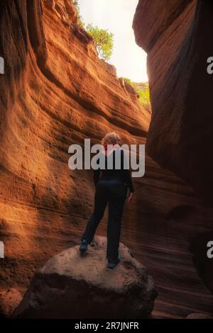 Unerkennbare Frau mit dem Rücken zum Himmel, in einem Canyon Stockfoto