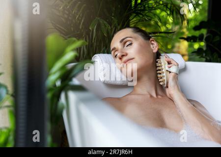 Frau genießt Wellness-Spa-Bad mit Körpermassagebürste Stockfoto