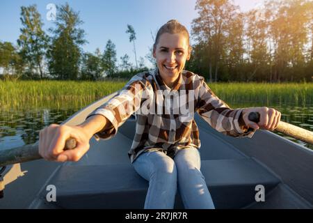 Lächelnde Frau rudert am sonnigen Sommertag auf dem See Stockfoto