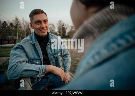 Nahaufnahme eines lächelnden, wunderschönen jungen Paares auf der Bank im Park Stockfoto