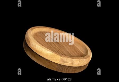 Eine runde Holzwanne, Makro, isoliert auf schwarzem Hintergrund. Stockfoto