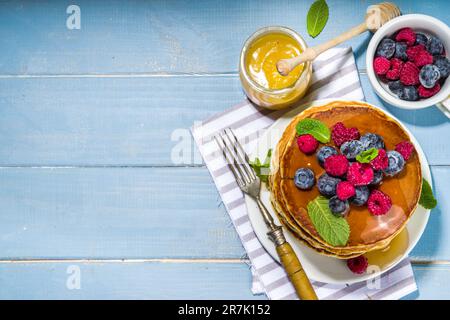 Teller mit leckeren traditionellen amerikanischen Pfannkuchen mit frischen Beeren und Sirup auf Küchentisch auf hellem Hintergrund Stockfoto