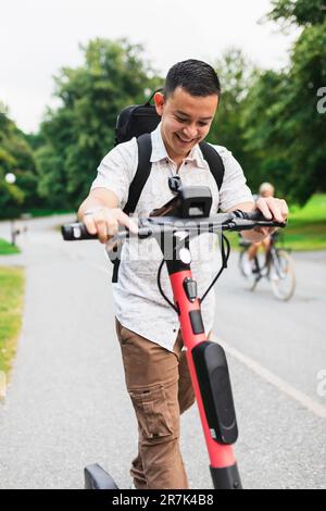 Ein Mann, der einen elektrischen Roller im Park fährt Stockfoto