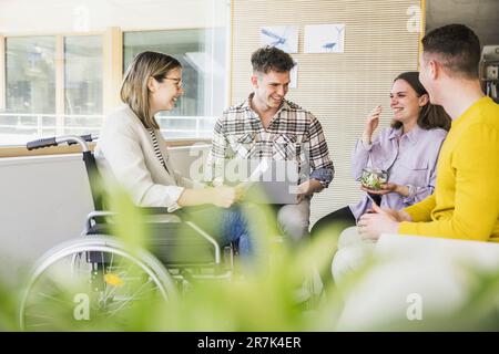 Junge Geschäftsleute, die sich im Büro treffen und eine Frau im Rollstuhl sitzen Stockfoto