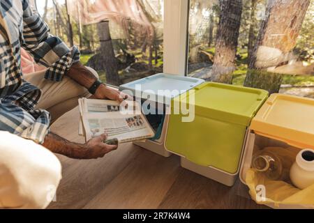 Ein Mann, der Altpapier in einen Mülltrennbehälter wirft Stockfoto