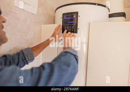 Mann, der das Smart-Home-Thermostat justiert Stockfoto