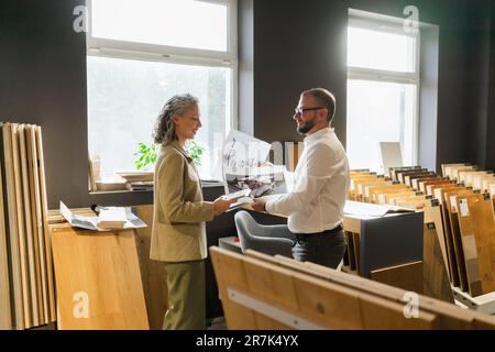 Zwei Kollegen mit einem Ausdruck eines Hauses und einem Bauplan im Architektenbüro Stockfoto