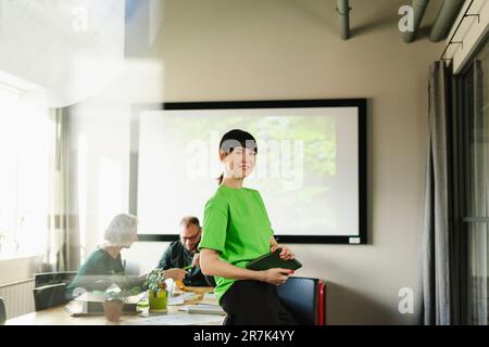 Porträt einer Frau, die während einer Besprechung im Konferenzraum ein grünes T-Shirt trägt Stockfoto