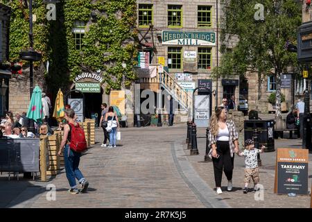 Menschen vor Pubs und Cafés im Stadtzentrum am 7. Juni 2023 in Hebden Bridge, Großbritannien. Die Hebden Bridge ist eine Marktstadt im Upper Calder Valley in West Yorkshire. In den 1970er und 1980er Jahren kam es in der Stadt zu einem Zustrom von Künstlern, Kreativen und alternativen Praktizierenden sowie Grün- und Neuzeitaktivisten. In jüngerer Zeit erlebten wohlhabendere Fachleute, die seinerseits einen Boom des Tourismus in die Gegend verzeichneten, der noch verschlimmert wurde, nachdem die populäre Verbrechensserie Happy Valley gedreht und in und um die Stadt gedreht wurde. Stockfoto