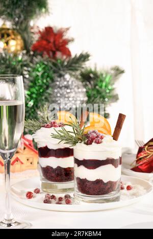 Weihnachts-Cranberry-Dessert-Tiramisu mit Mascarpone und Schlagsahne, Schokoladen-Kekskrümel und Cranberry-Marmelade, garniert mit Orangenscheiben, Dose Stockfoto