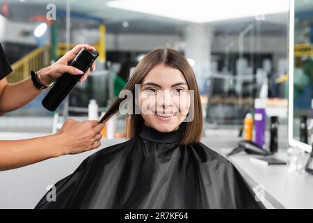 Salonservice, Haarspray, Friseurstyling Haare einer Kundin mit Nasenpiercing, fröhliche brünette Frau mit kurzen Haaren, Schönheitssalon, Haar V Stockfoto