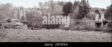 Einfarbiges Panorama der Kalemouth Suspension Bridge über den Teviot River zwischen Kelso und Jedburgh an der schottischen Grenze, Großbritannien. Stockfoto