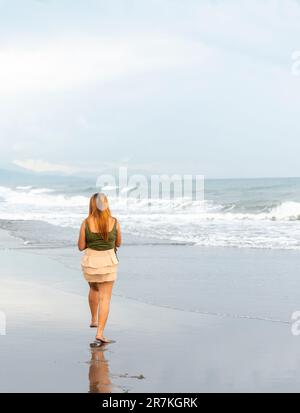 Halten Sie ihr Handy für Selfies, an einem Strand in der Nähe von Manila in der Dämmerung, schlendern Sie ziellos durch die warmen Küstengewässer, entlang des sanften Sandes, haben Sie Spaß, tanzen Sie herum Stockfoto