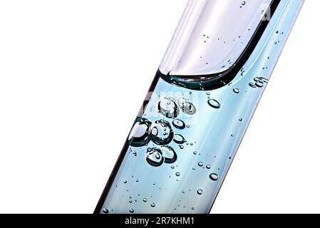 Reagenzglas mit transparenter Flüssigkeit und isolierten Blasen auf weißem Hintergrund. Makro. Stockfoto