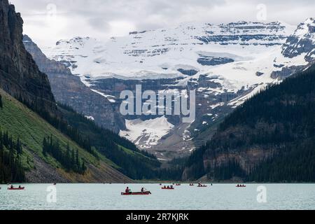 Lake Louise, ab, Kanada - August 2022; Blick auf das gletschergespeiste Wasser von Lake Louise mit einer großen Anzahl von Touristen in Kanus auf dem See gegen den Stockfoto