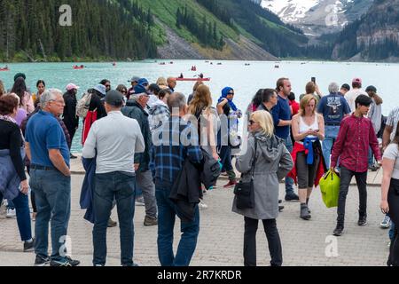 Lake Louise, ab, Kanada - August 2022; sehen Sie viele Touristen am Ufer des von Gletschern gespeisten Lake Louise mit vielen Kanus auf dem See vor der Kulisse von Th Stockfoto