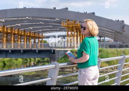 Eine Touristin, die auf einem Tablet einen Reiseleiter konsultierte und die Straße beobachtete, erstaunt. Eine Frau mittleren Alters reist durch die Stadt. Stadtverkehr c Stockfoto