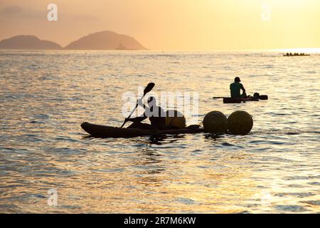 Silhouetten von Menschen in Kanus bei Sonnenaufgang am Copacabana-Strand in Rio de Janeiro, Brasilien. Stockfoto