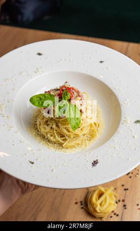 Eine appetitliche Platte mit Spaghetti in einer köstlichen Tomatensoße garniert mit frischen Basilikumblättern Stockfoto