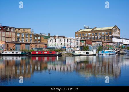 Schmalboote und Lagerhäuser entlang der River Lea Navigation in Hackney Wick, East London, Großbritannien, im Sommer Stockfoto