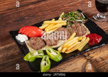 Türkisches Fleischklößchen, traditionelles Kofte. Scharfe Fleischbällchen Kebab oder Kebap. Türkische Fleischbällchen mit frischen grünen Paprika und Gurken. Stockfoto