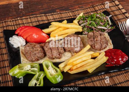 Türkisches Fleischklößchen, traditionelles Kofte. Scharfe Fleischbällchen Kebab oder Kebap. Türkische Fleischbällchen mit frischen grünen Paprika und Gurken. Stockfoto