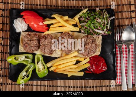 Türkisches Fleischklößchen, traditionelles Kofte. Scharfe Fleischbällchen Kebab oder Kebap. Türkische Fleischbällchen mit frischen grünen Paprika und Gurken. Stockfoto