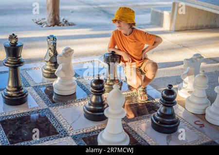 Vater und Sohn spielen Schach und verbringen Zeit zusammen im Freien. Kind spielt Schach Stockfoto