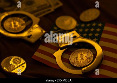 Golden Bitcoins Kryptowährung mit Handschellen auf Dollarscheinen. Konzept der digitalen Kriminalität, der Festnahme oder des Hacking. Handschellen Dollar und Bitcoins auf dem Tisch Stockfoto
