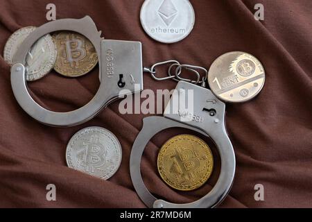 Golden Bitcoins Kryptowährung mit Handschellen auf Dollarscheinen. Konzept der digitalen Kriminalität, der Festnahme oder des Hacking. Handschellen Dollar und Bitcoins auf dem Tisch Stockfoto
