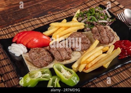 Türkisches Fleischklößchen, traditionelles Kofte. Scharfe Fleischbällchen Kebab oder Kebap. Türkische Fleischbällchen mit frischen grünen Paprika und Gurken. Stockfoto