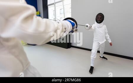 Porträt von zwei Fechtern vor dem Hintergrund einer Sportarena. Das Konzept des Zaunens. Duell. Gemischte Medien Stockfoto