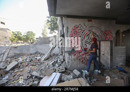 Beit Lahia, Palästinensische Gebiete. 16. Juni 2023. Der palästinensische Künstler Ayman Alhossary, 35, malt arabische Kalligraphie auf die Überreste eines Hauses, das bei den jüngsten Kämpfen zwischen Israel und Gaza in Beit Lahia, nördlicher Gazastreifen, zerstört wurde. Kredit: Mohammed Talatene/dpa/Alamy Live News Stockfoto