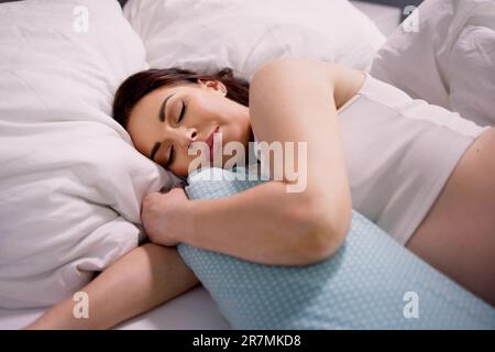 Schwangere Frau, Die Auf Einem Bett Mit Speziellem Kissen Schläft Stockfoto