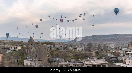 Ein Bild von Heißluftballons, die bei Sonnenaufgang über den historischen Nationalpark Goreme und die Stadt Goreme fliegen. Stockfoto