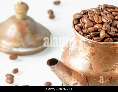 Kaffeekanne aus Kupfer im Retro-Stil, die bis zur Spitze mit Kaffeebohnen gefüllt ist Stockfoto