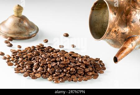 Kaffeebohnen aus einer alten Kupferkaffeekanne, die auf der Seite lag. Stockfoto